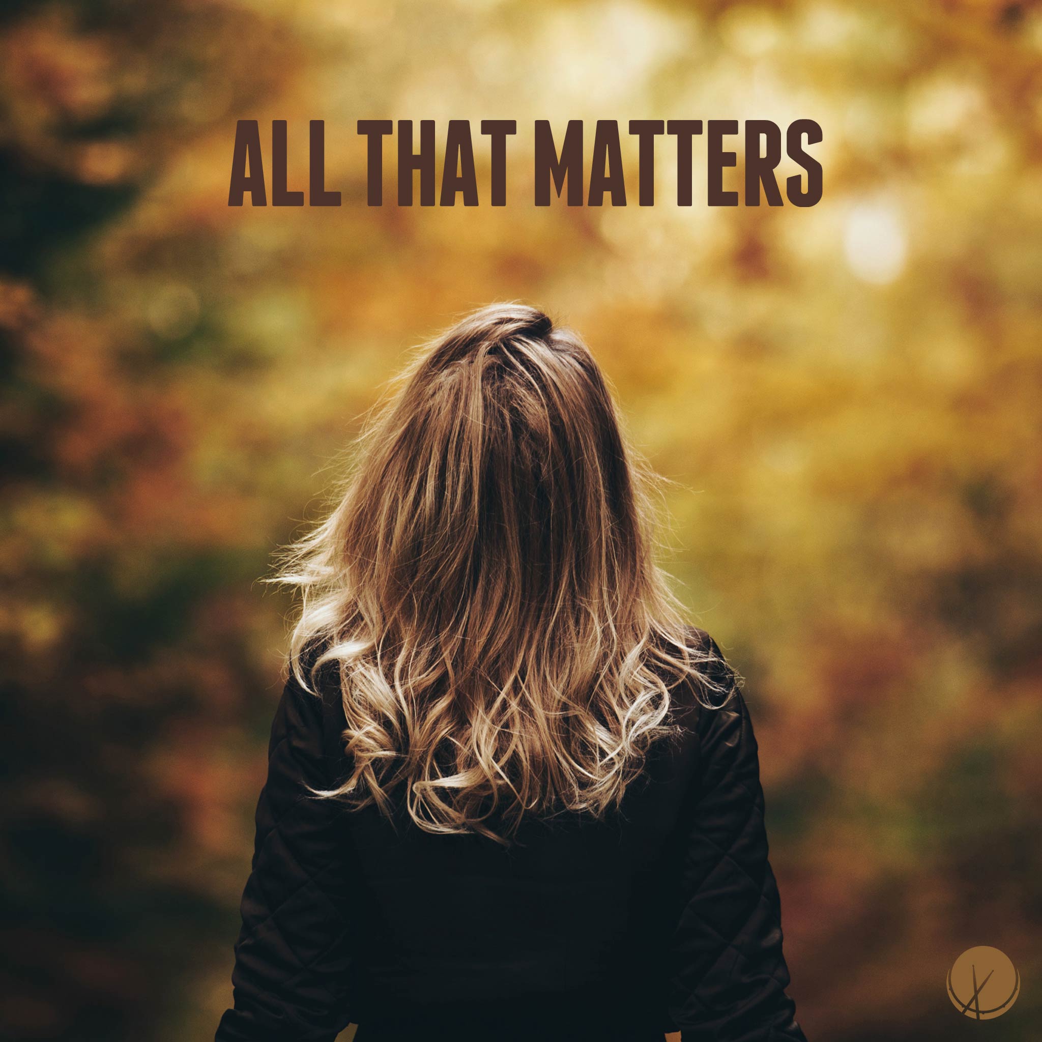 Professional photograph featuring a blonde woman in a black jacket surrounded by autumn leaves. She is facing out towards blurred autumn scenery. Title: "All That Matters."